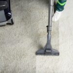 High Angle View Of Person Cleaning White Carpet With Professional Vacuum Cleaner